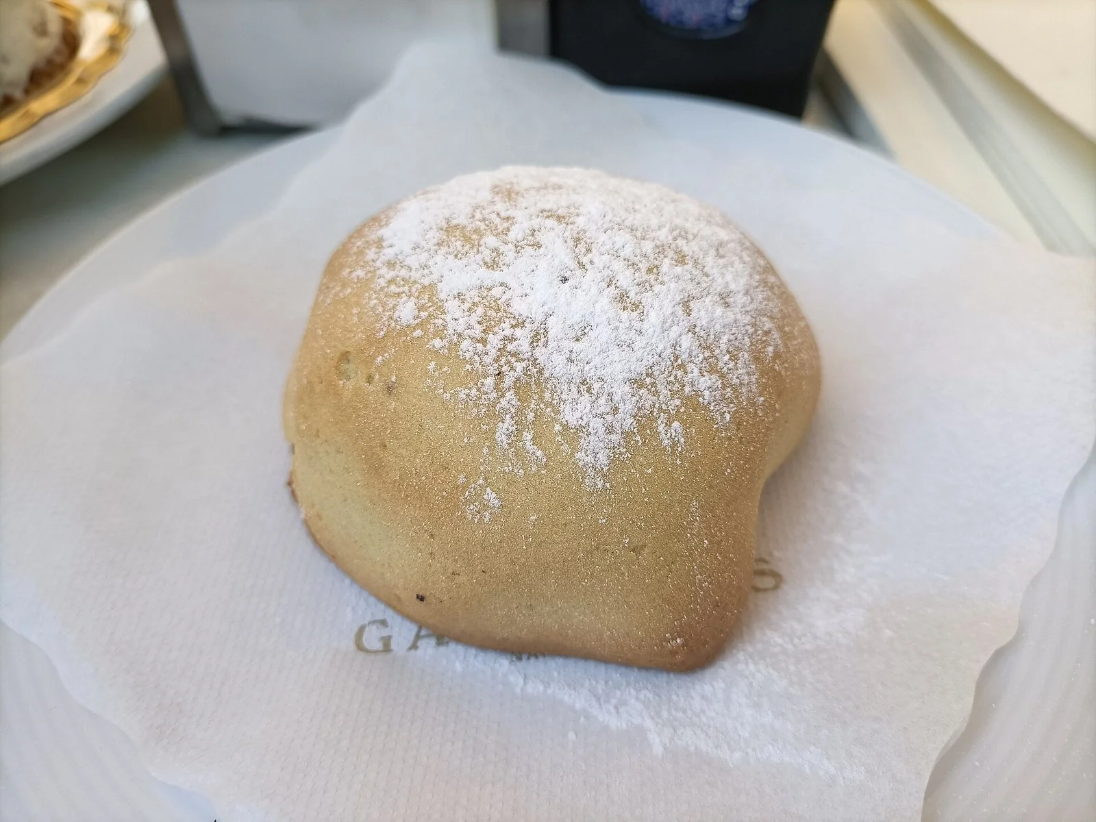 紙を敷いた皿の上の、粉砂糖をふった丸い焼き菓子スフォリアテッラ。